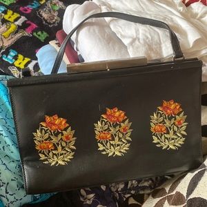 A small black bag embellished with flowers on front and back